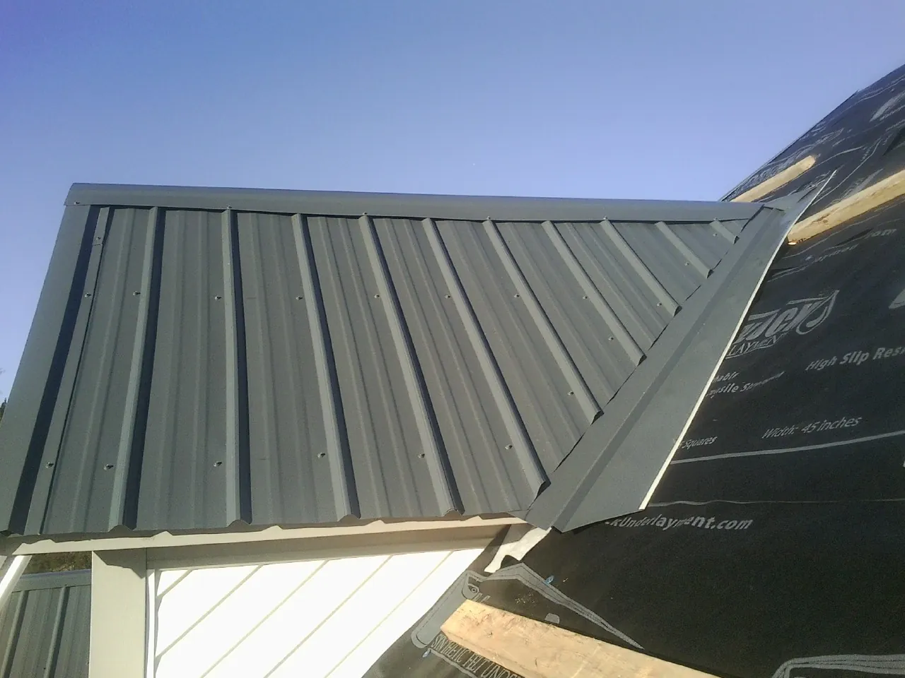 Gray metal roof panels going on over a garage gable in Bushwood