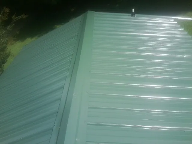 New green metal panels meeting at the ridge of a roof — Flat Roof Repair work by our crew in Bushwood