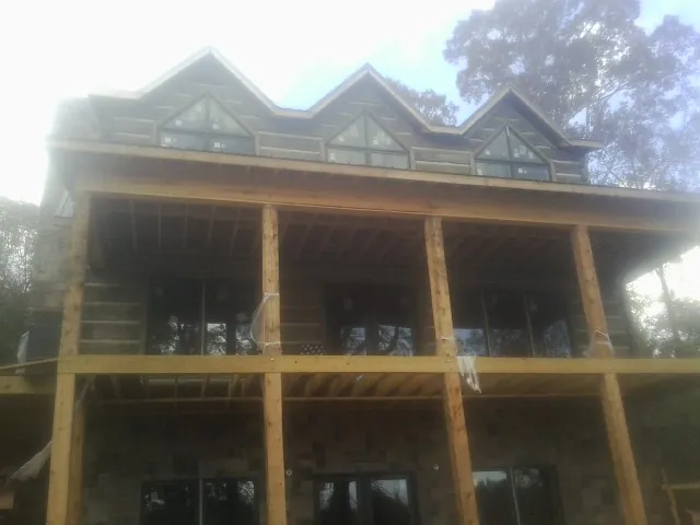 Dormers and porch framing on a large log home under construction — Roof Coating work by our crew in Bushwood