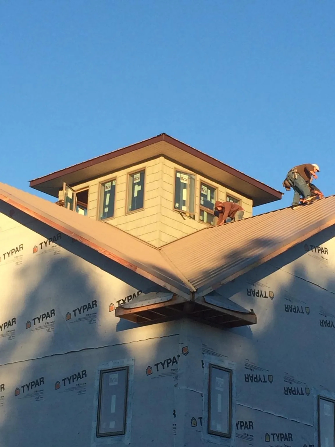 Roofers working around a rooftop cupola on a new metal roof at sunset — Roof Waterproofing in Bushwood by Roofing Brothers